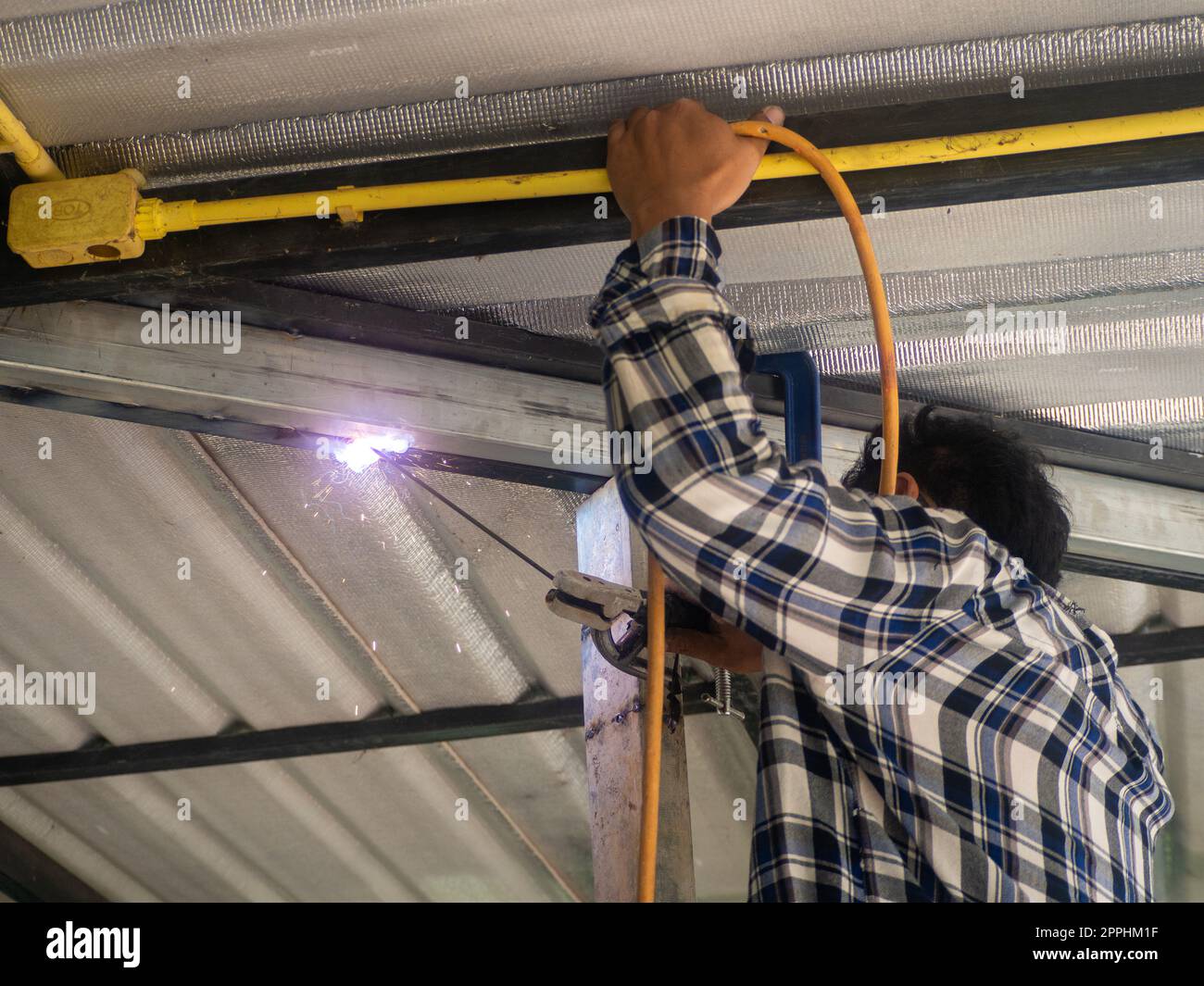 Un soudeur travaille sur un châssis en acier. Sur le chantier. Banque D'Images