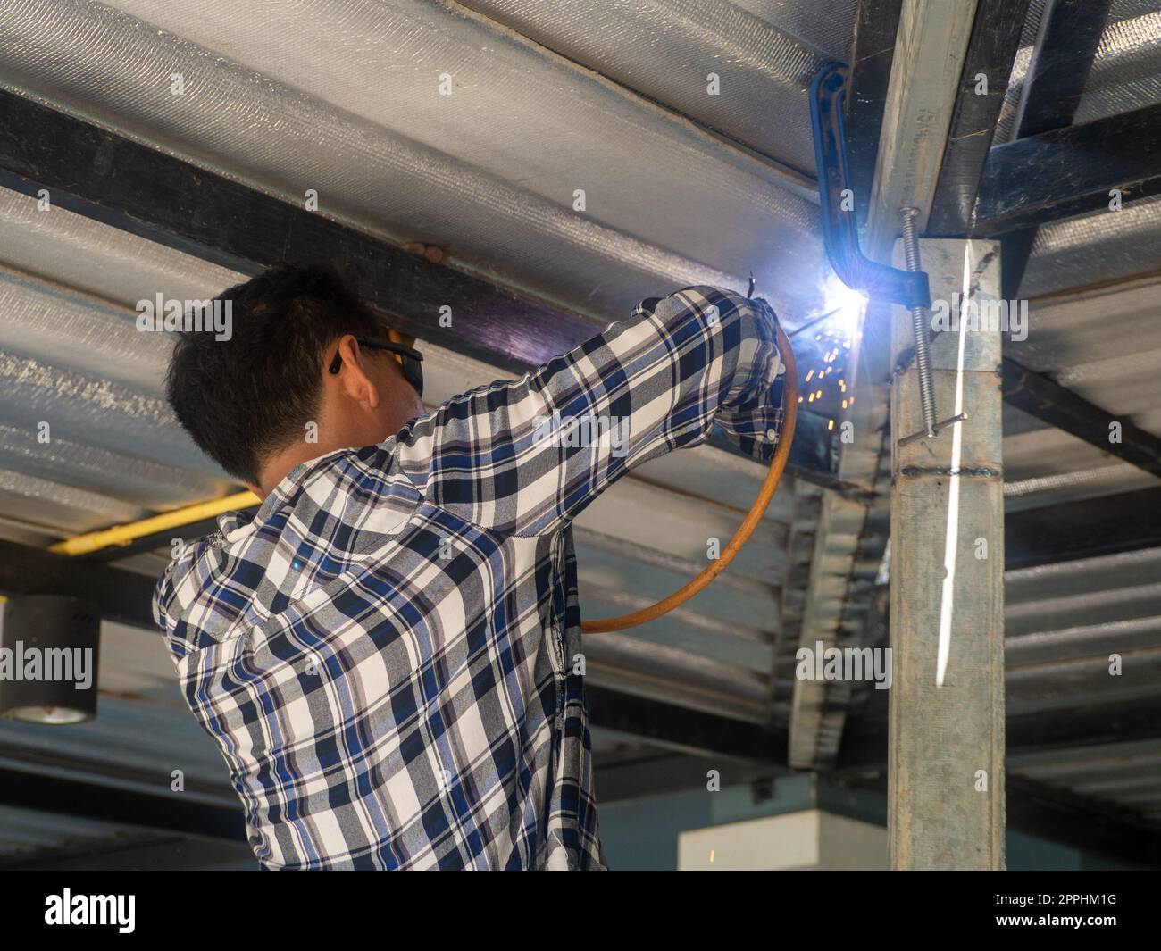 Un soudeur travaille sur un châssis en acier. Sur le chantier. Banque D'Images