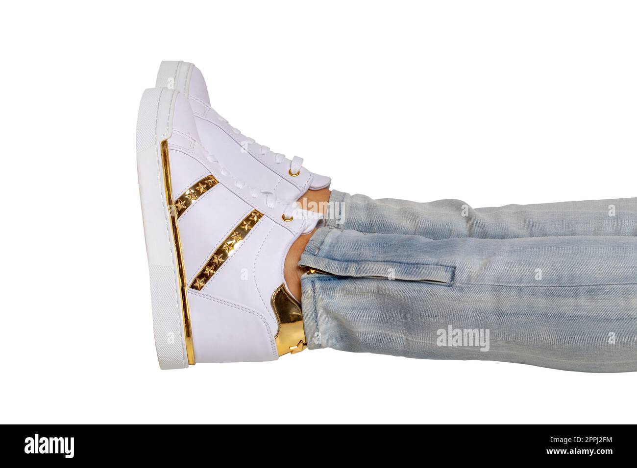 Jambes des femmes en jeans et baskets. Jambes de femme dans un pantalon en denim léger portant une sneaker blanche moderne. Chaussures blanches à la mode. Masque. Photographie macro. Banque D'Images