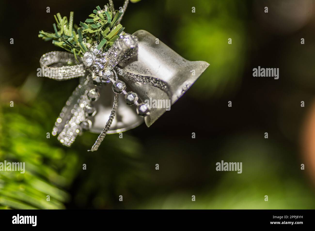 pot de cloche accroché sur un arbre de noël avec détail de fond vert Banque D'Images
