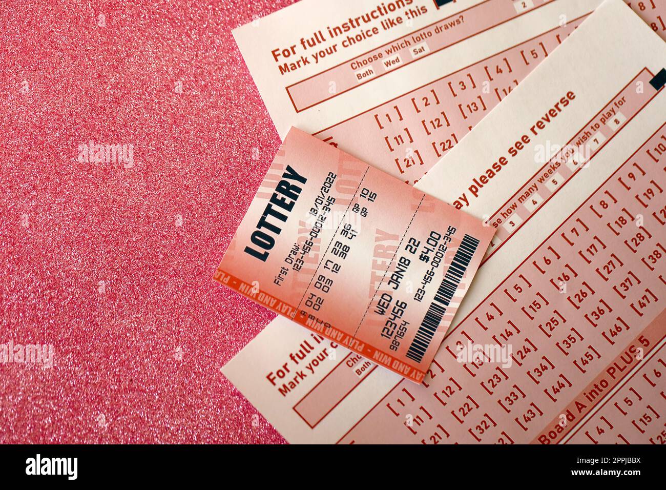 Billet de loterie rouge se trouve sur des feuilles de jeu roses avec des numéros pour marquer pour jouer à la loterie. Concept de jeu de loterie ou dépendance au jeu. Gros plan Banque D'Images