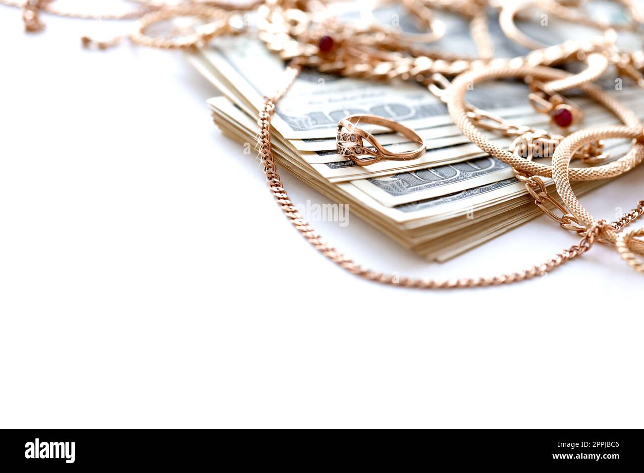 Beaucoup d'anneaux de bijoux en or coûteux, boucles d'oreilles et colliers avec une grande quantité de billets de dollar US sur fond blanc. Prêteur sur gage ou bijouterie Banque D'Images