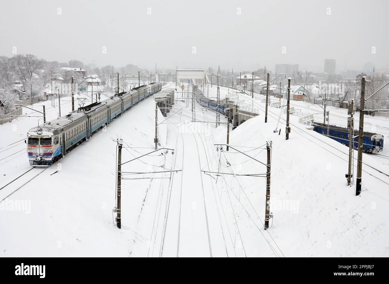 Un long train de voitures de tourisme se déplace le long de la voie ferrée. Paysage ferroviaire en hiver après les chutes de neige Banque D'Images
