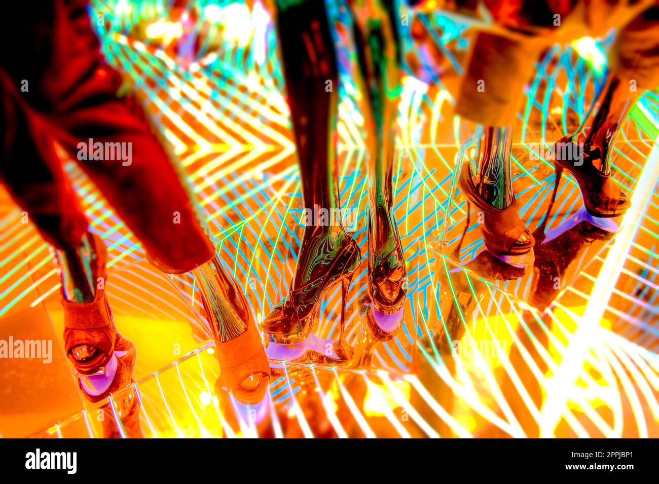 Jambes et pieds de mannequin sur un sol miroir avec éclairage coloré Banque D'Images