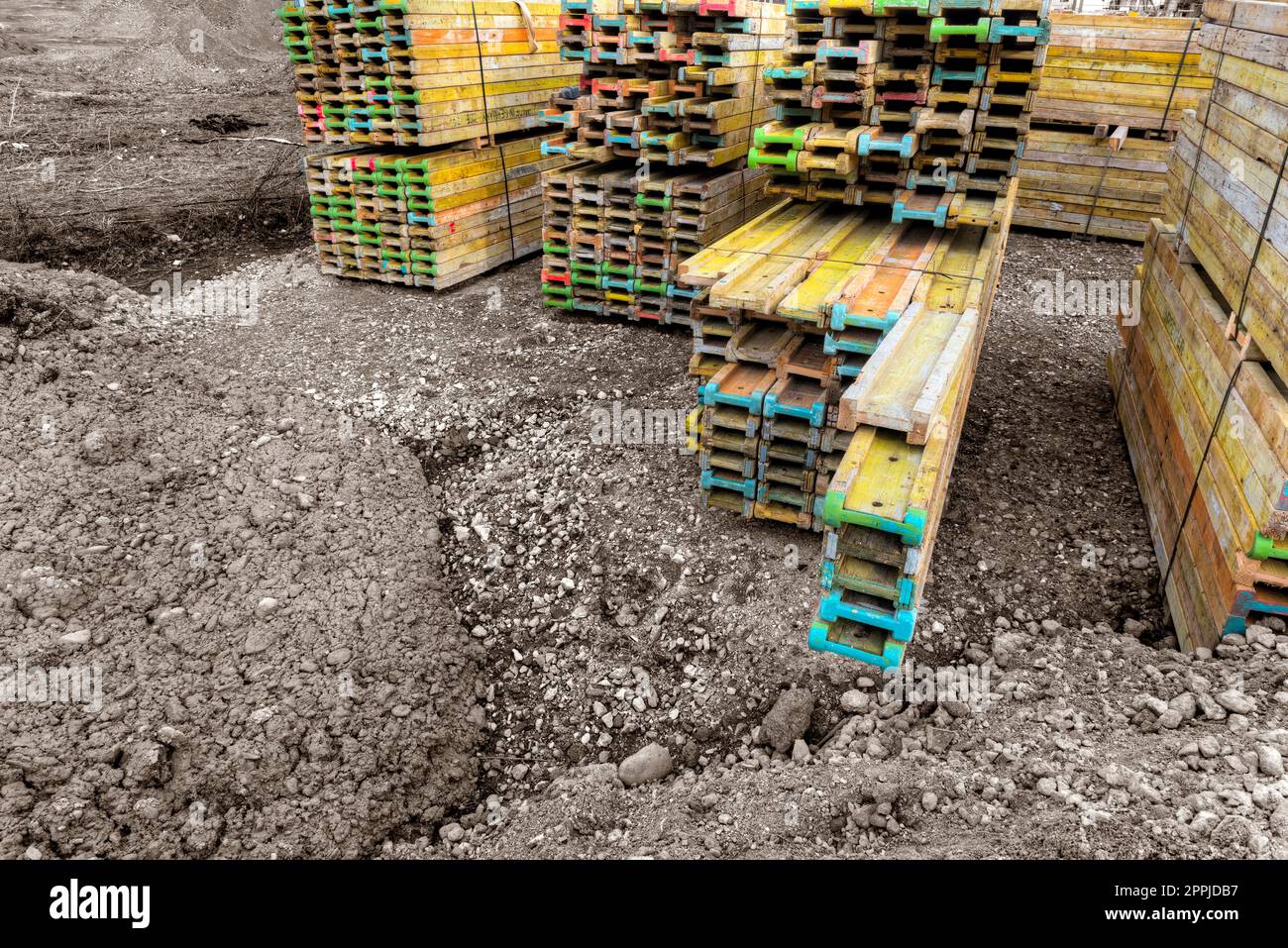 Des poutres en bois de construction colorées sont empilées et triées sur un chantier de construction Banque D'Images