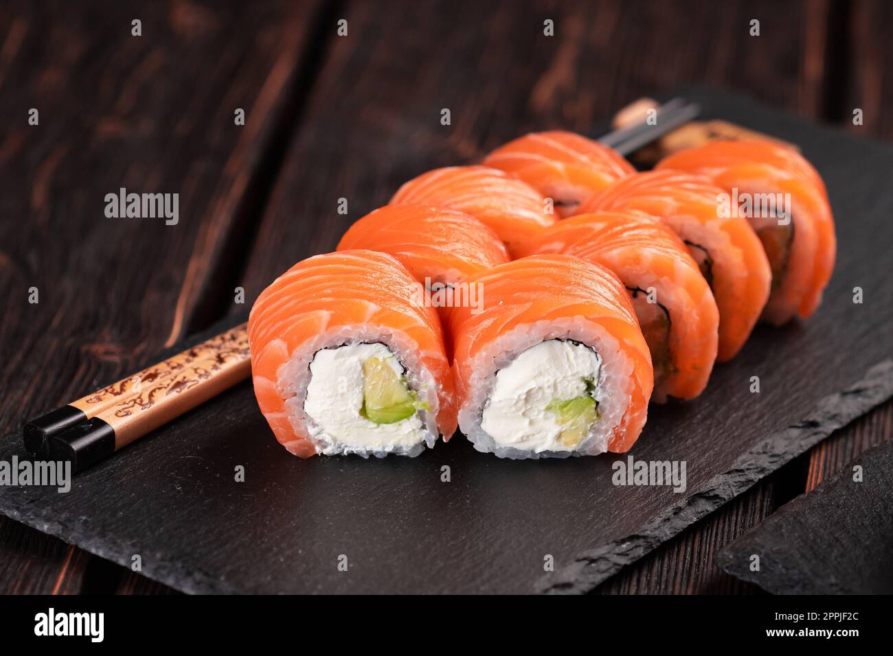 Les sushis roulent philadelphie avec du saumon et du concombre et du fromage à la crème sur fond noir. Menu sushi. Concept alimentaire japonais Banque D'Images