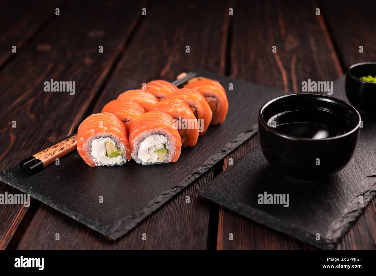 Les sushis roulent philadelphie avec du saumon et du concombre et du fromage à la crème sur fond noir. Menu sushi. Concept alimentaire japonais Banque D'Images