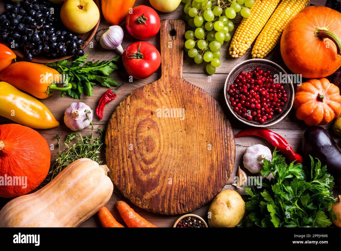 Divers légumes biologiques et planche à découper vide sur table en bois, espace de copie. Cuisiner des aliments biologiques sains de fond. Récolte d'automne légumes agricoles Banque D'Images