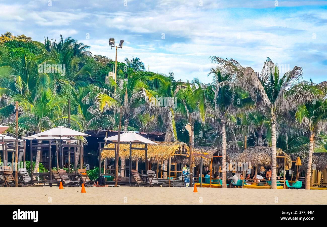 Palmiers parasols chaises longues plage Resort Zicatela Puerto Escondido Mexique. Banque D'Images