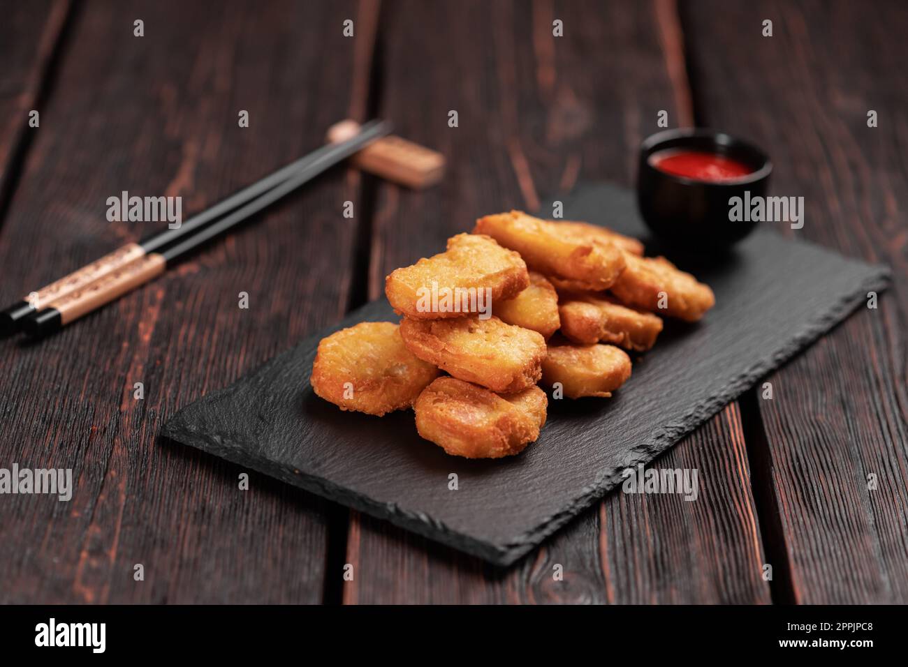 Morceaux de poulet frits sur un plateau de pierre avec baguettes - cuisine asiatique Banque D'Images