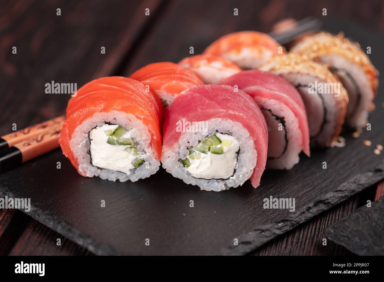 Petits pains avec saumon de poisson et crevettes et sushi à l'anguille maguro au thon avec baguettes - cuisine asiatique et japonaise Banque D'Images