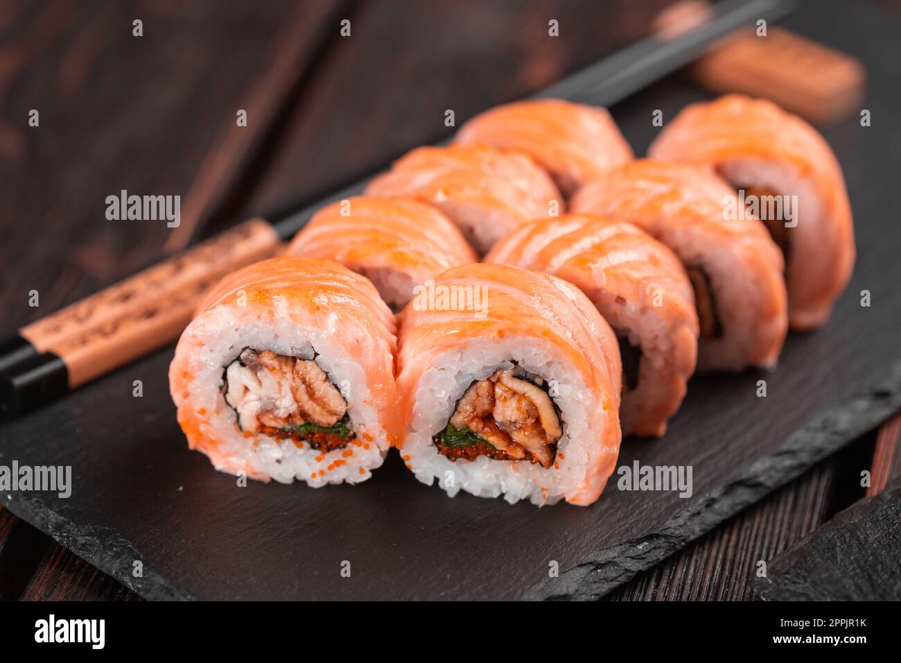 Sushi roul maguro avec saumon, anguille fumée, avocat et tobiko sur le tableau noir. Menu sushi. Cuisine japonaise. Banque D'Images
