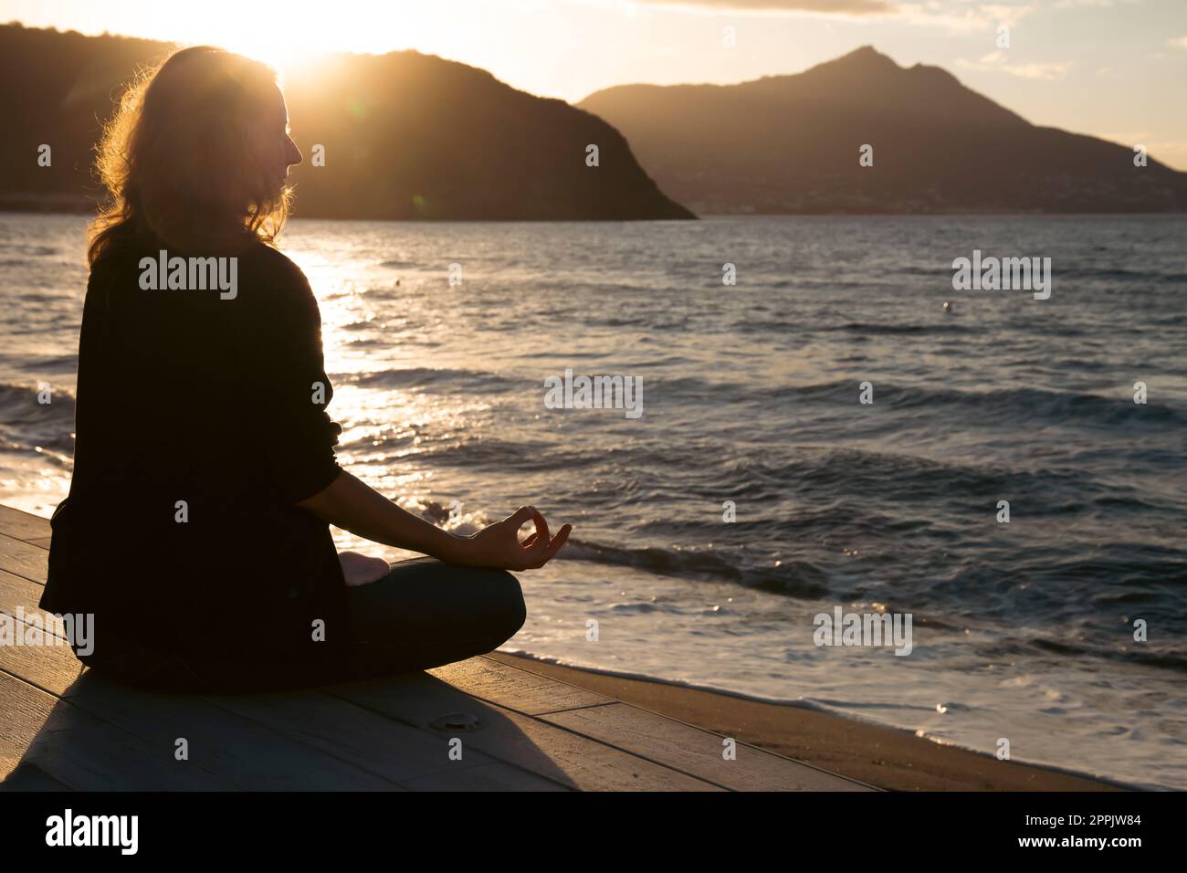 Femme méditant dehors au coucher du soleil Banque D'Images