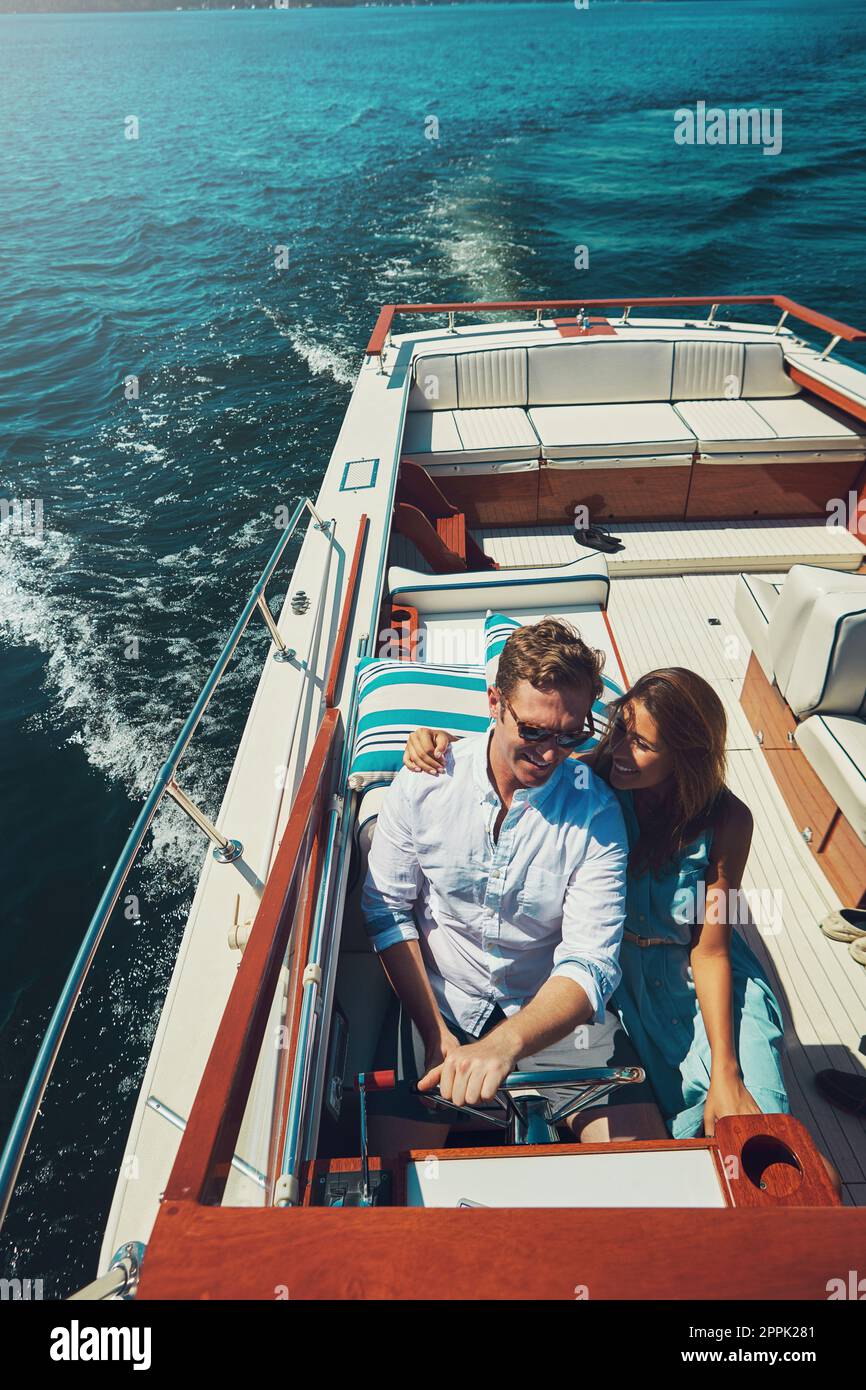 Liaison sur leur bateau. Photo en grand angle d'un jeune couple affectueux qui navigue en haute mer dans son yacht. Banque D'Images