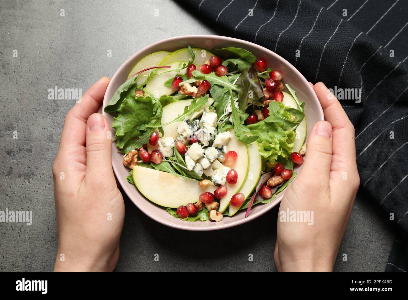 Femme avec une savoureuse salade de poires à table grise, vue de dessus Banque D'Images