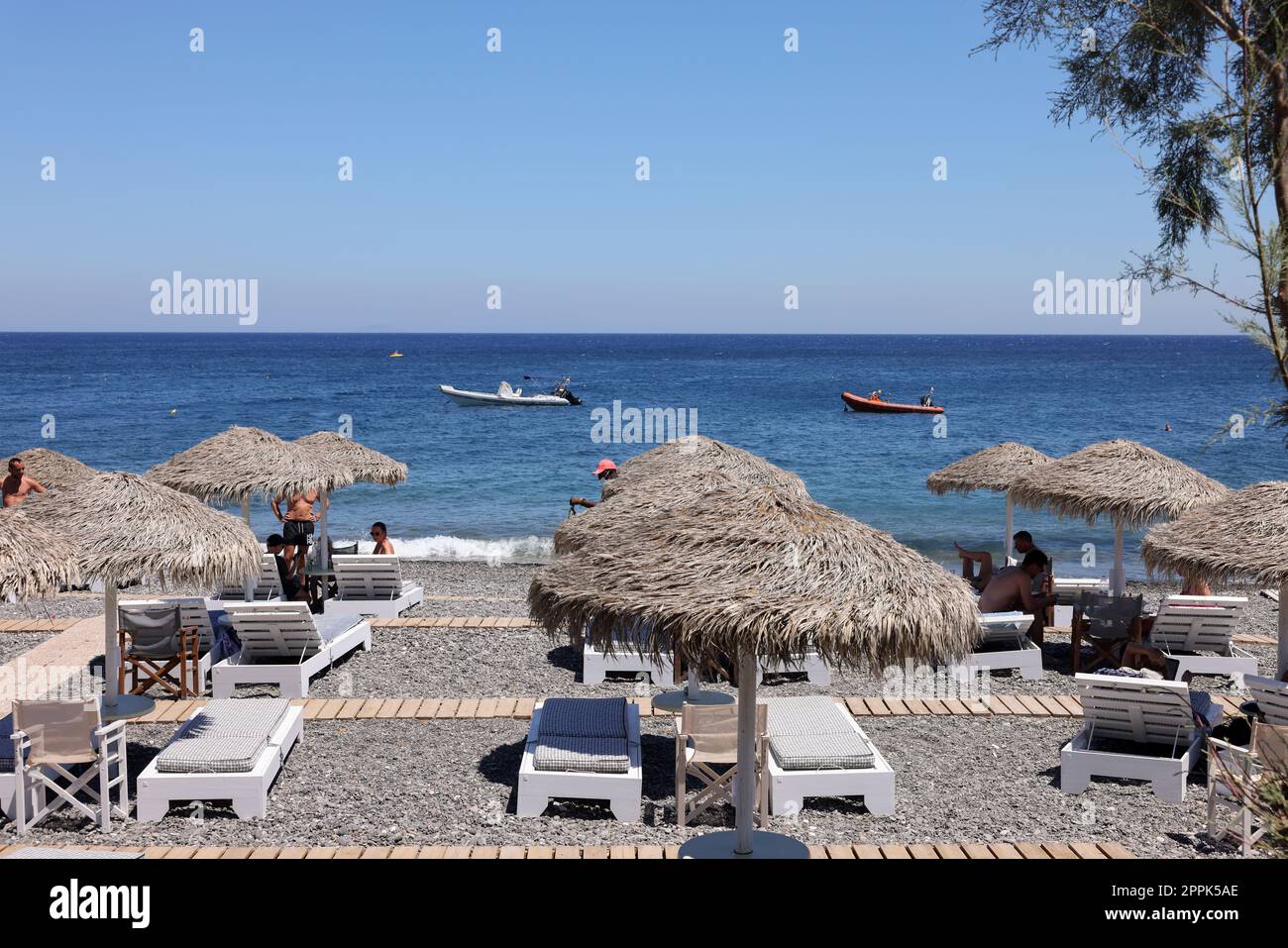 Chaises longues sur la plage volcanique noire de Kamari à Santorin.Cyclades, Grèce Banque D'Images