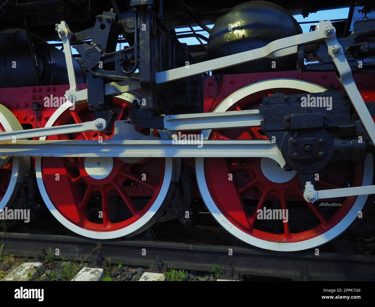 Roues rétro vintage d'une locomotive ou d'un train en gros plan. Grandes roues rouges en métal lourd avec mécanismes de guidage de piston. Locomotive des 19e - 20e siècles avec une machine à vapeur. Banque D'Images