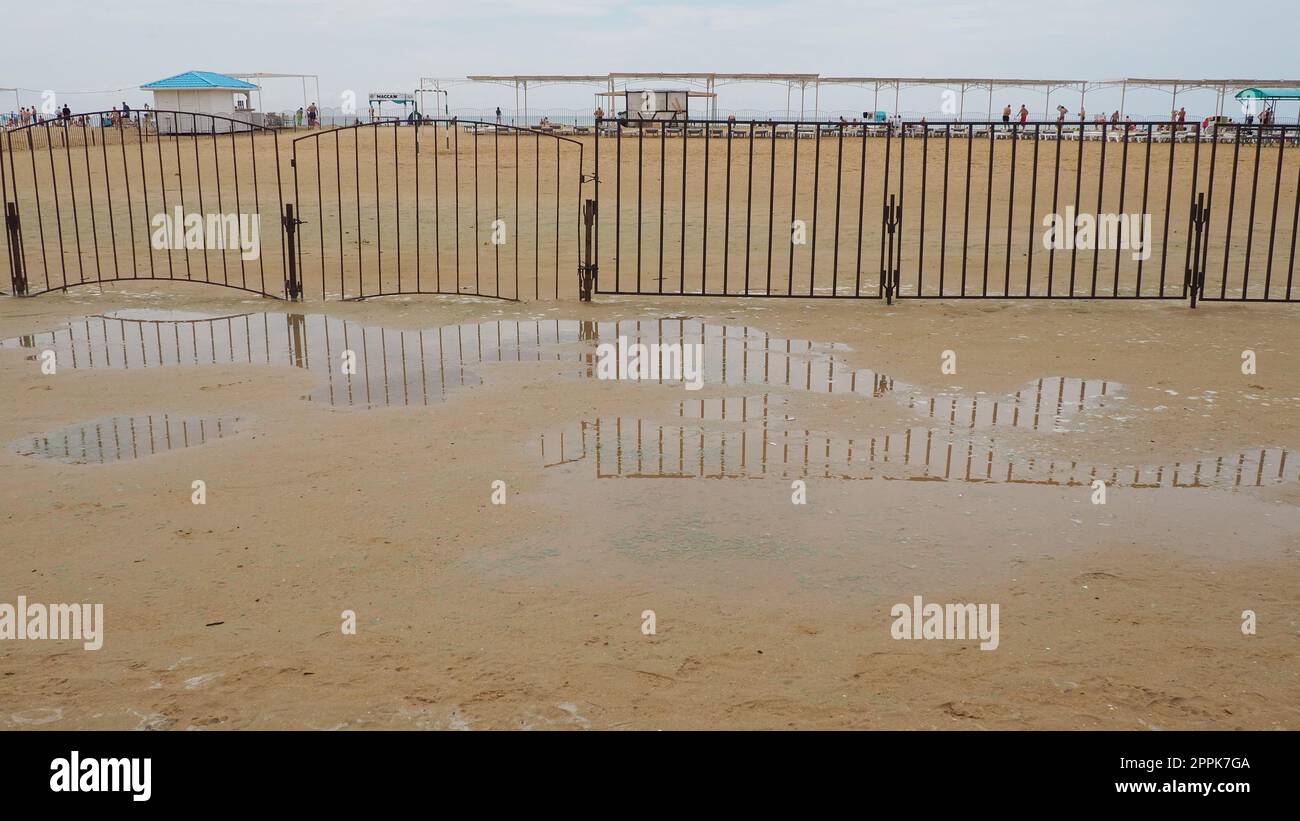 Vityazevo Russie, août 10 2021 Une flaque d'eau sur une plage de sable de quartz médicinale après de fortes pluies. Conséquences du mauvais temps et du typhon. Le bord de la plage saison des vacances. Touristes en arrière-plan Banque D'Images