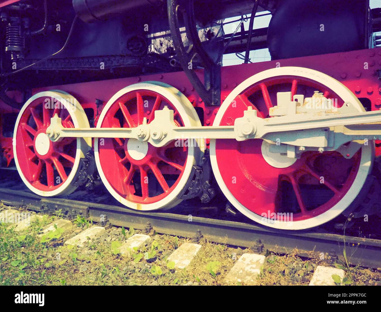 Roues rétro vintage d'une locomotive ou d'un train en gros plan. Grandes roues rouges en métal lourd avec mécanismes de guidage de piston. Locomotive des 19e - 20e siècles avec une machine à vapeur. Style rétro Banque D'Images