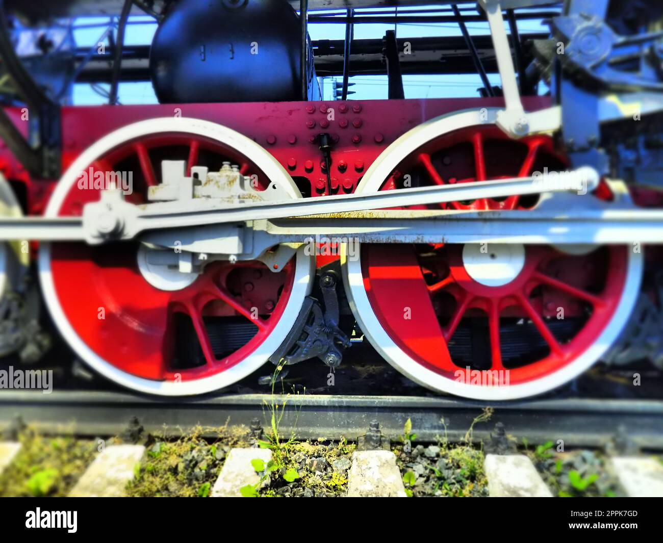 Roues rétro vintage d'une locomotive ou d'un train en gros plan. Grandes roues rouges en métal lourd avec mécanismes de guidage de piston. Locomotive des 19e - 20e siècles avec une machine à vapeur. Photo éclatante et éclatante Banque D'Images