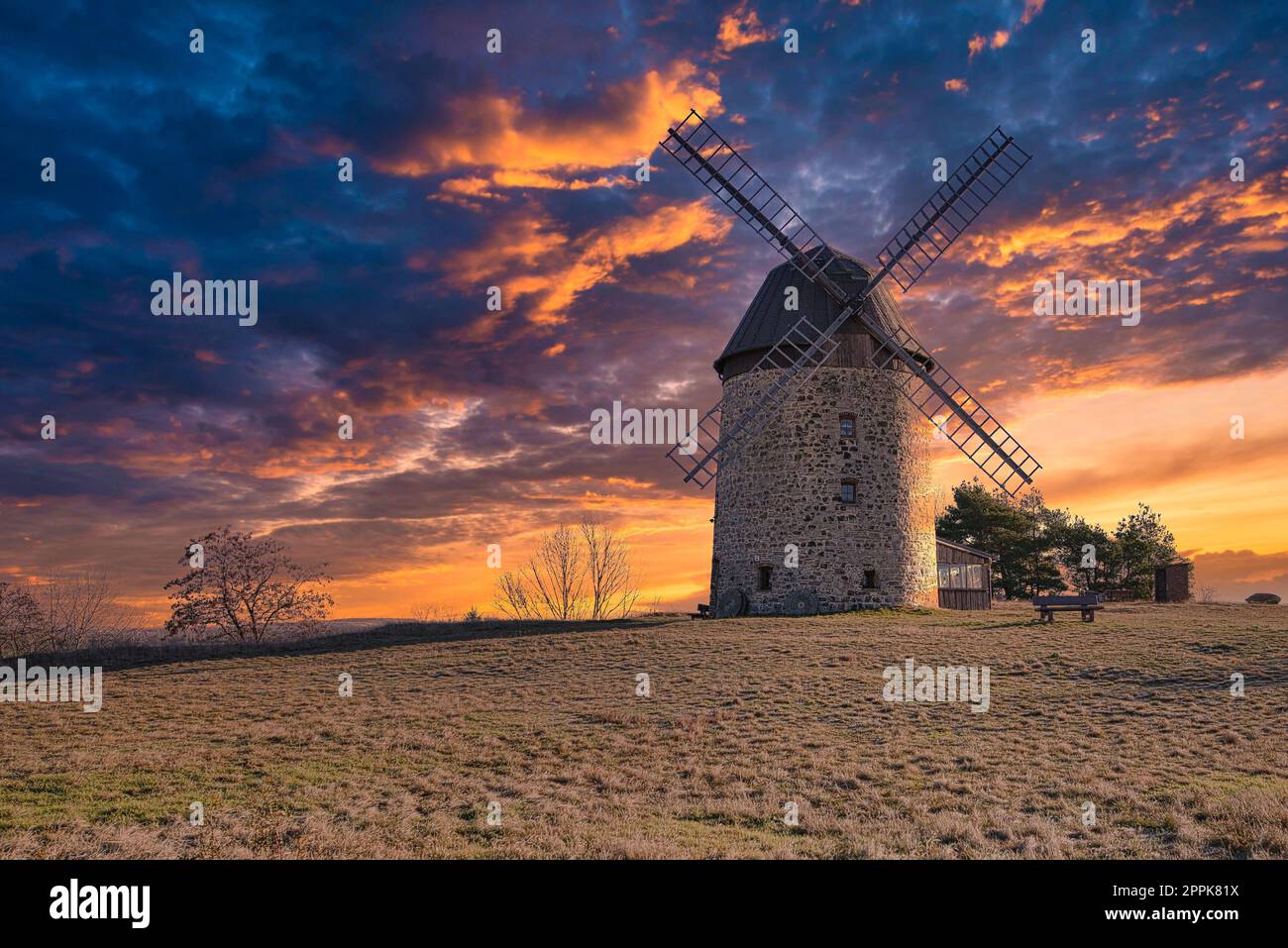 Moulin à vent dans le champ au coucher du soleil. Banque D'Images