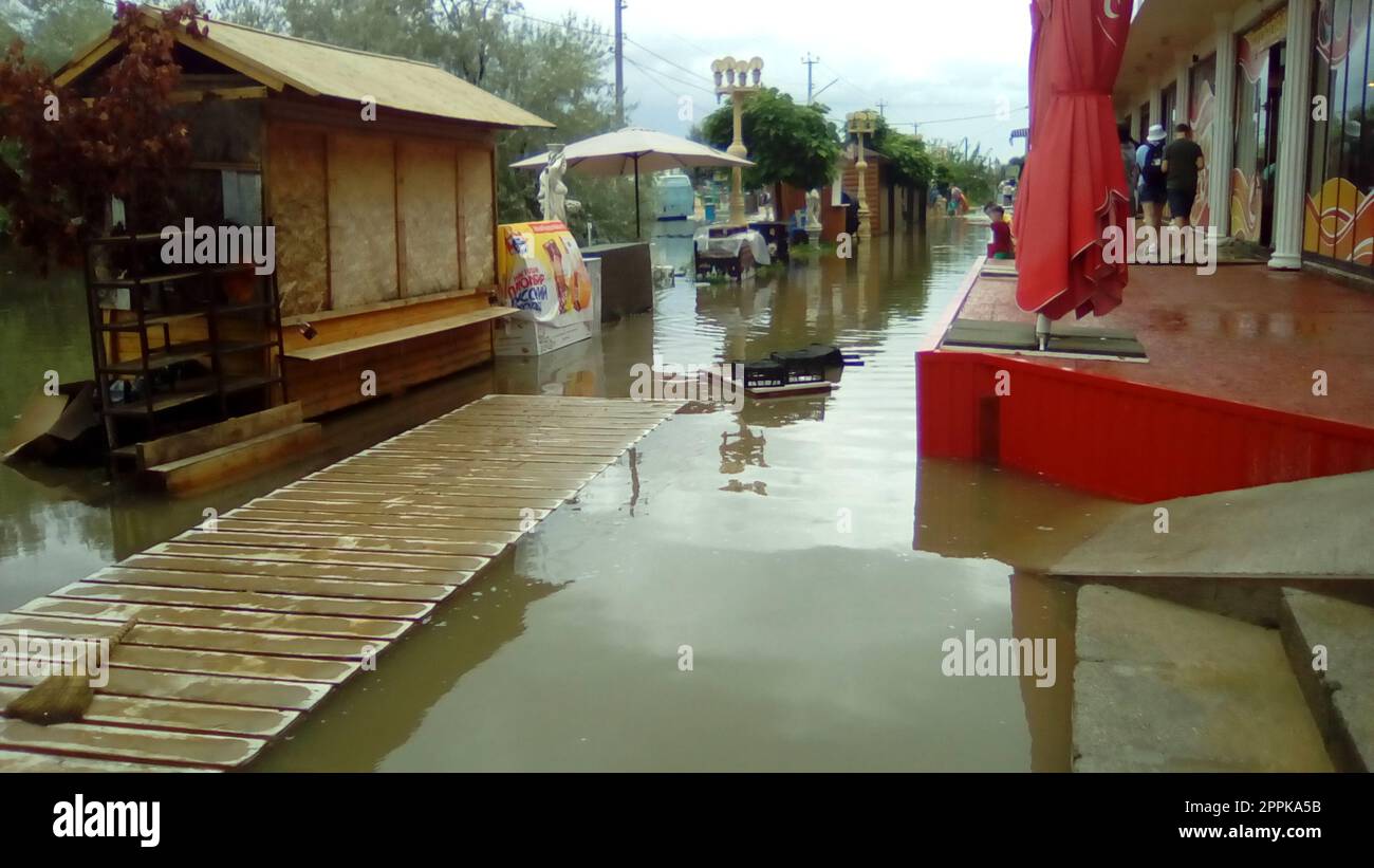 Anapa, Russie le 13 août 2021 inondations causées par de fortes pluies et des pluies torrentielles. Conséquences d'un typhon, d'un cyclone ou d'un ouragan. Rue commerçante inondée d'eau sale. Effets personnels mouillés et allées de plage Banque D'Images