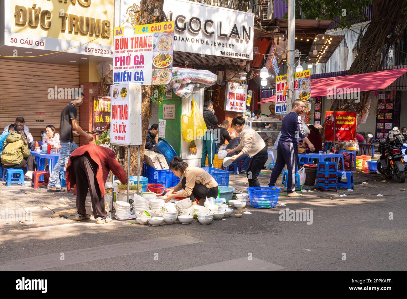 laver la vaisselle dans la rue à Hanoi, Vietnam Banque D'Images