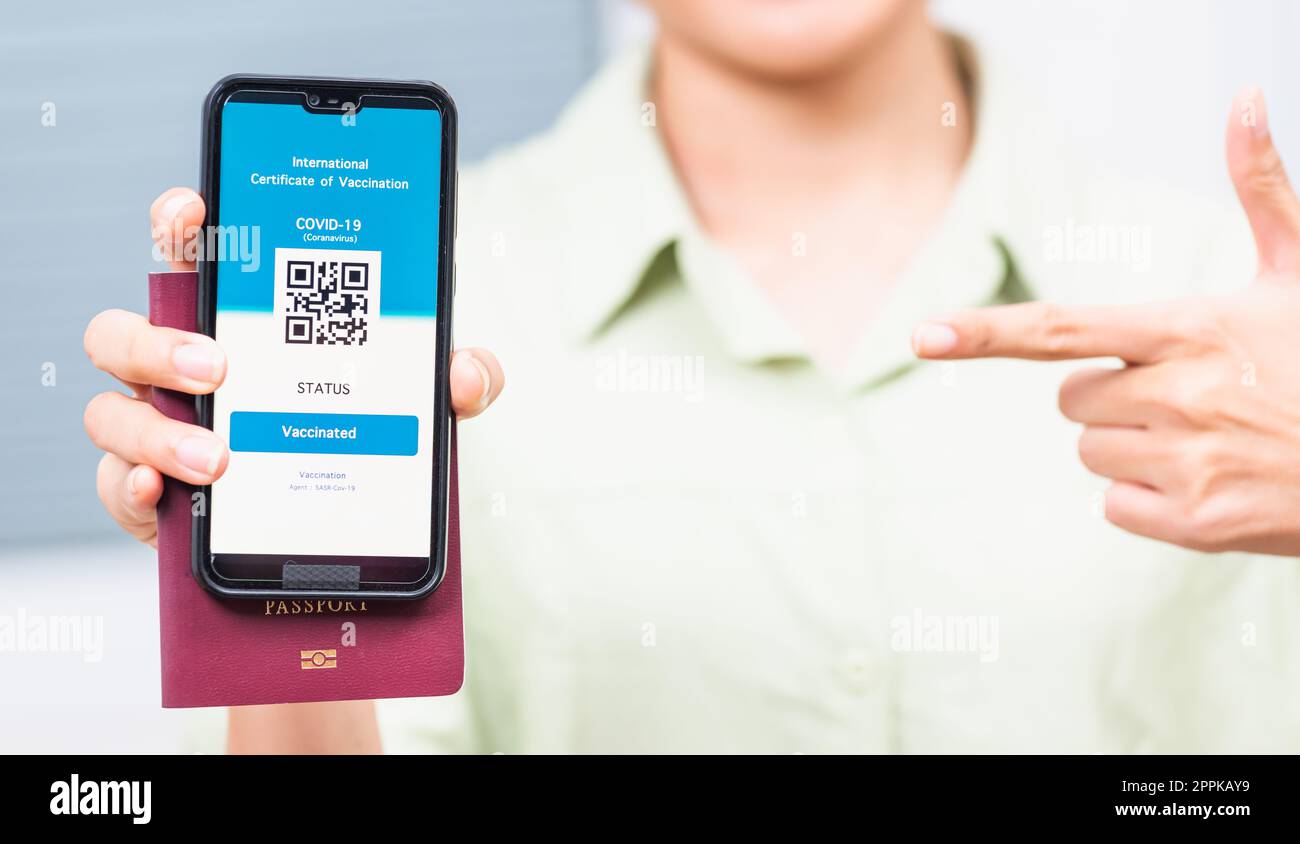 Voyageur femme souriante titulaire d'un passeport sanitaire de certification de vaccination sur smartphone Banque D'Images