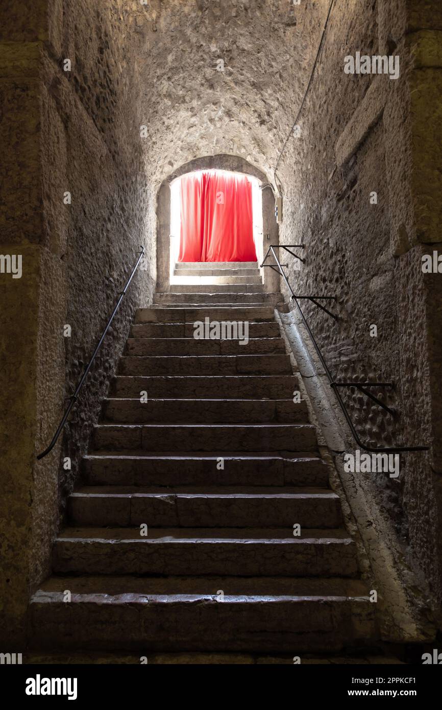 Vieux couloir avec rideau rouge au bout Concept de mystère, gothique, évasion, espoir. Banque D'Images