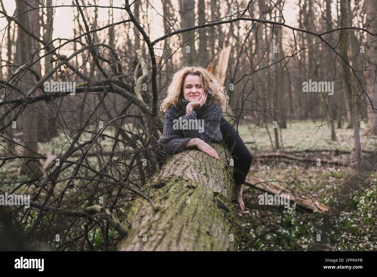 Une dame positive se reposant sur une photographie pittoresque d'arbre tombé Banque D'Images