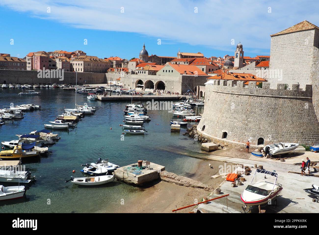 Dubrovnik, Croatie, 14 août 2022. Port de ville en été, attraction touristique. Les touristes marchent, montent dans les bateaux et les bateaux et font des excursions en bateau. Mer Adriatique. Un résident local joue avec un chien. Vieux forts. Banque D'Images