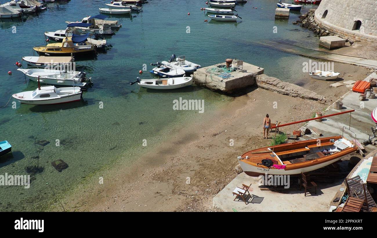 Dubrovnik, Croatie, 14 août 2022. Port de ville en été, attraction touristique. Les touristes marchent, montent dans les bateaux et les bateaux et font des excursions en bateau. Mer Adriatique. Un résident local joue avec un chien. Vieux forts. Banque D'Images