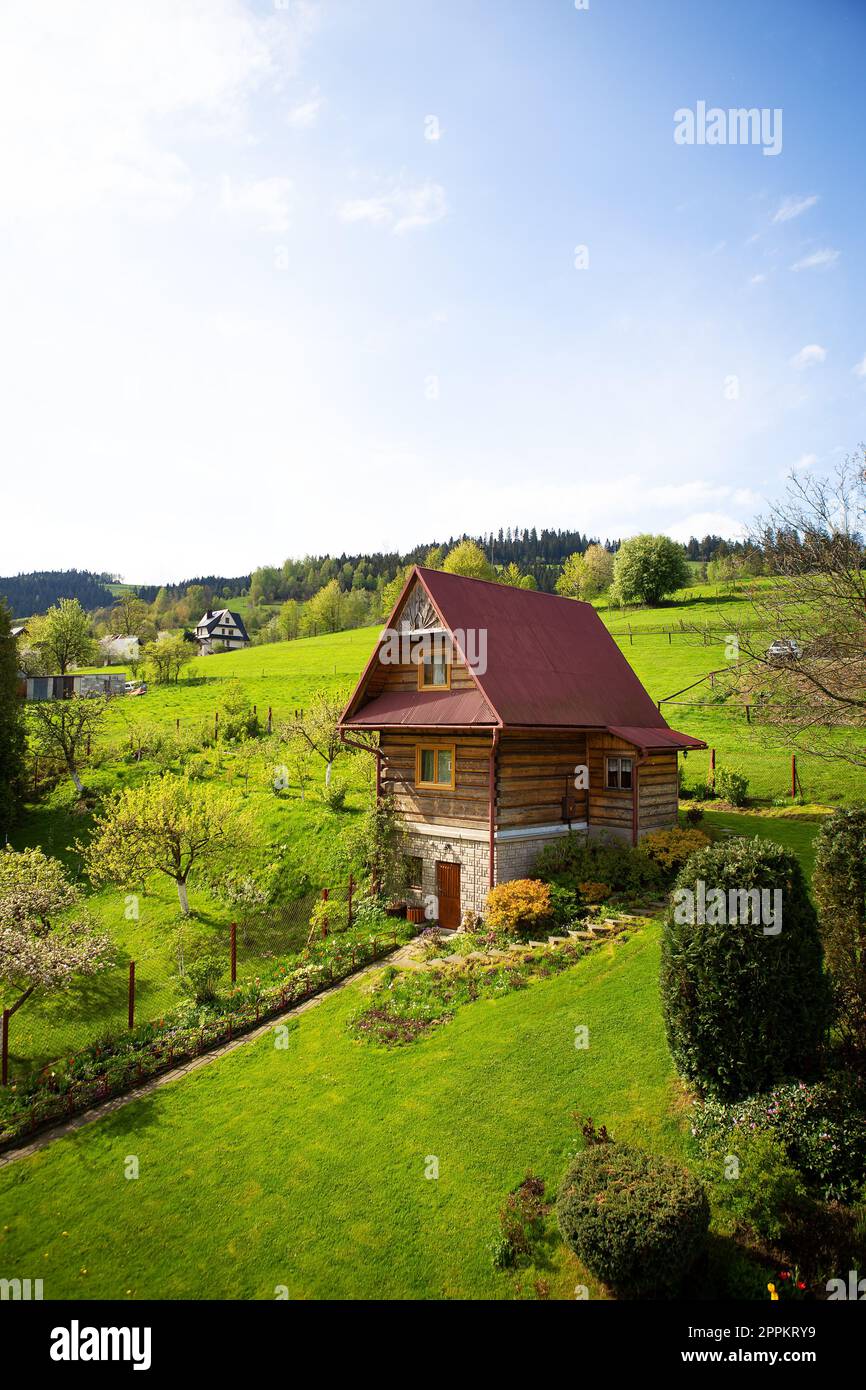 Vieux chalet en bois dans une vallée sur une colline, beau ciel bleu. Aménagement paysager. Vue depuis la fenêtre. Banque D'Images