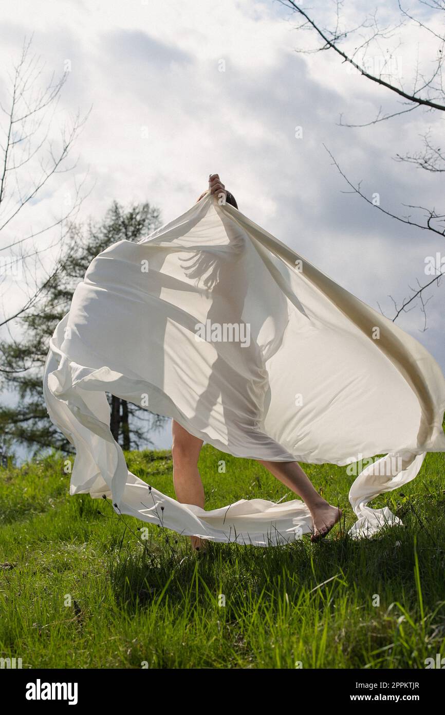 Lady tournant avec un tissu blanc dans la photographie pittoresque de prairie Banque D'Images