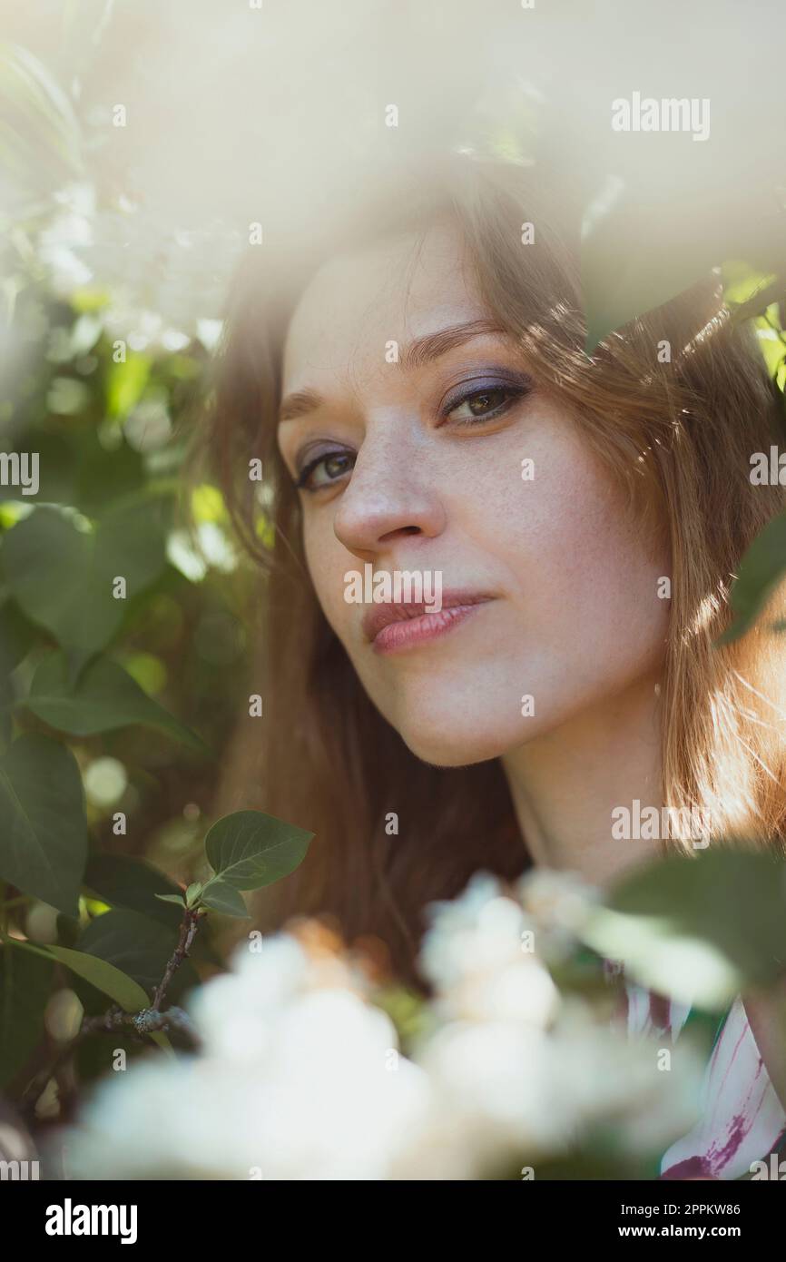Femme en gros plan avec un maquillage lumineux entouré d'une photo de portrait de fleurs blanches Banque D'Images