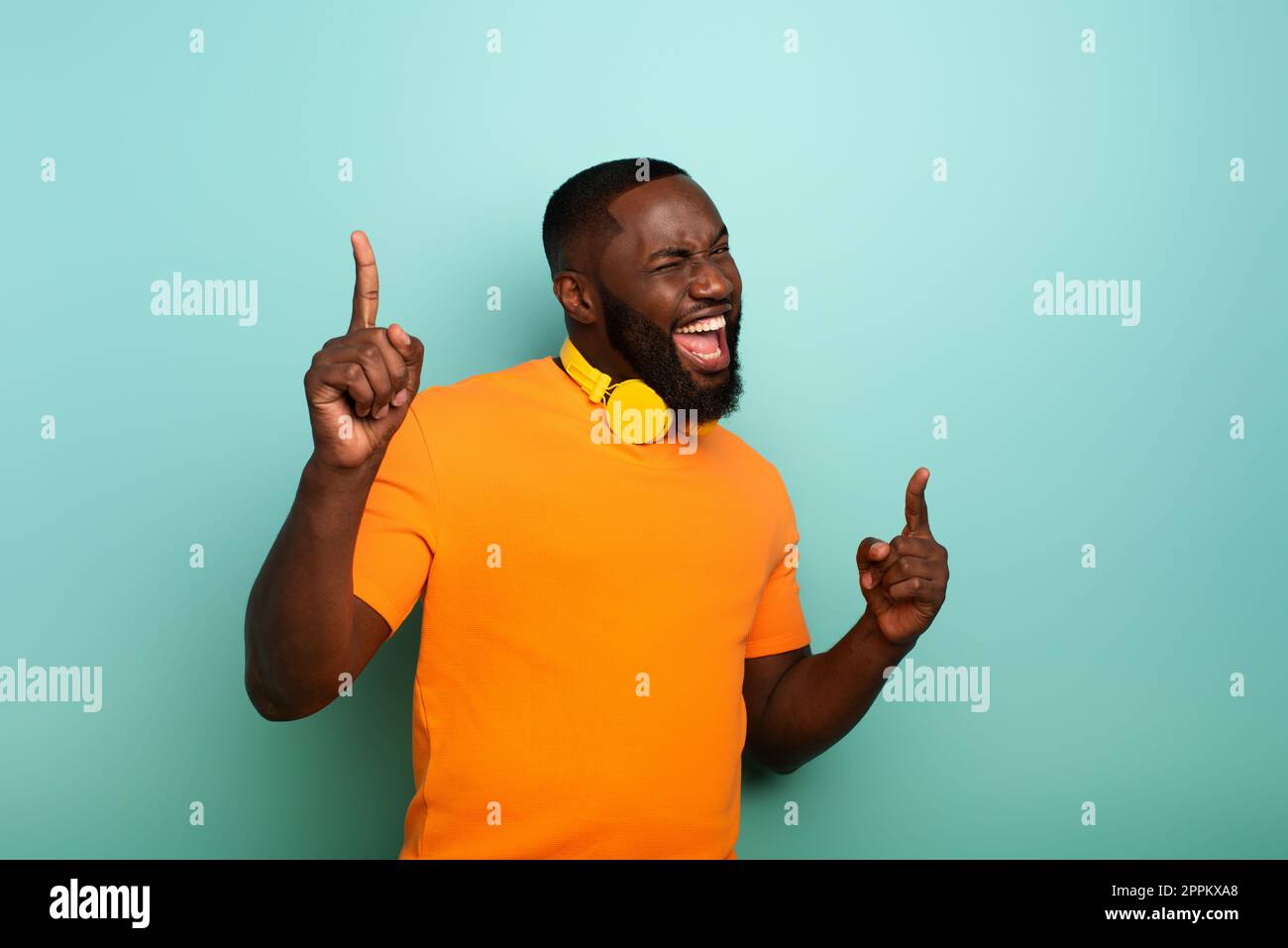 Garçon avec casque jaune écoute de la musique et des danses et énergique expression émotionnelle. Banque D'Images