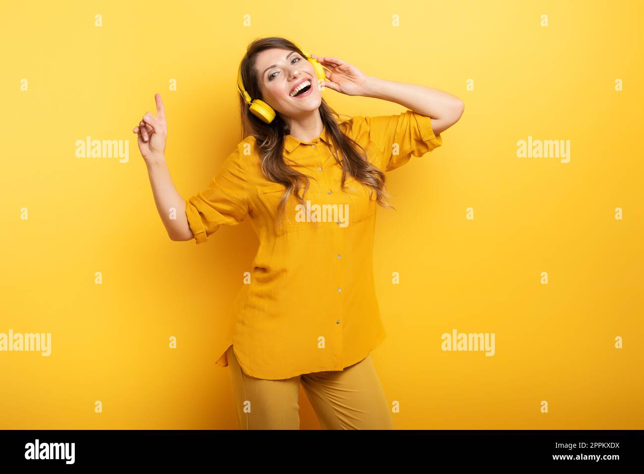 Fille avec casque jaune écoute de la musique et des danses et énergique expression émotionnelle. Banque D'Images
