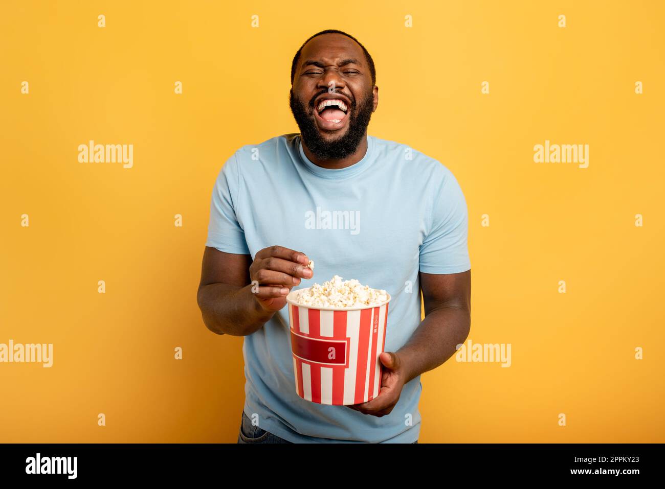 Garçon a plaisir à regarder un film. Concept de divertissement et de diffusion en continu de la télévision. Fond rouge Banque D'Images