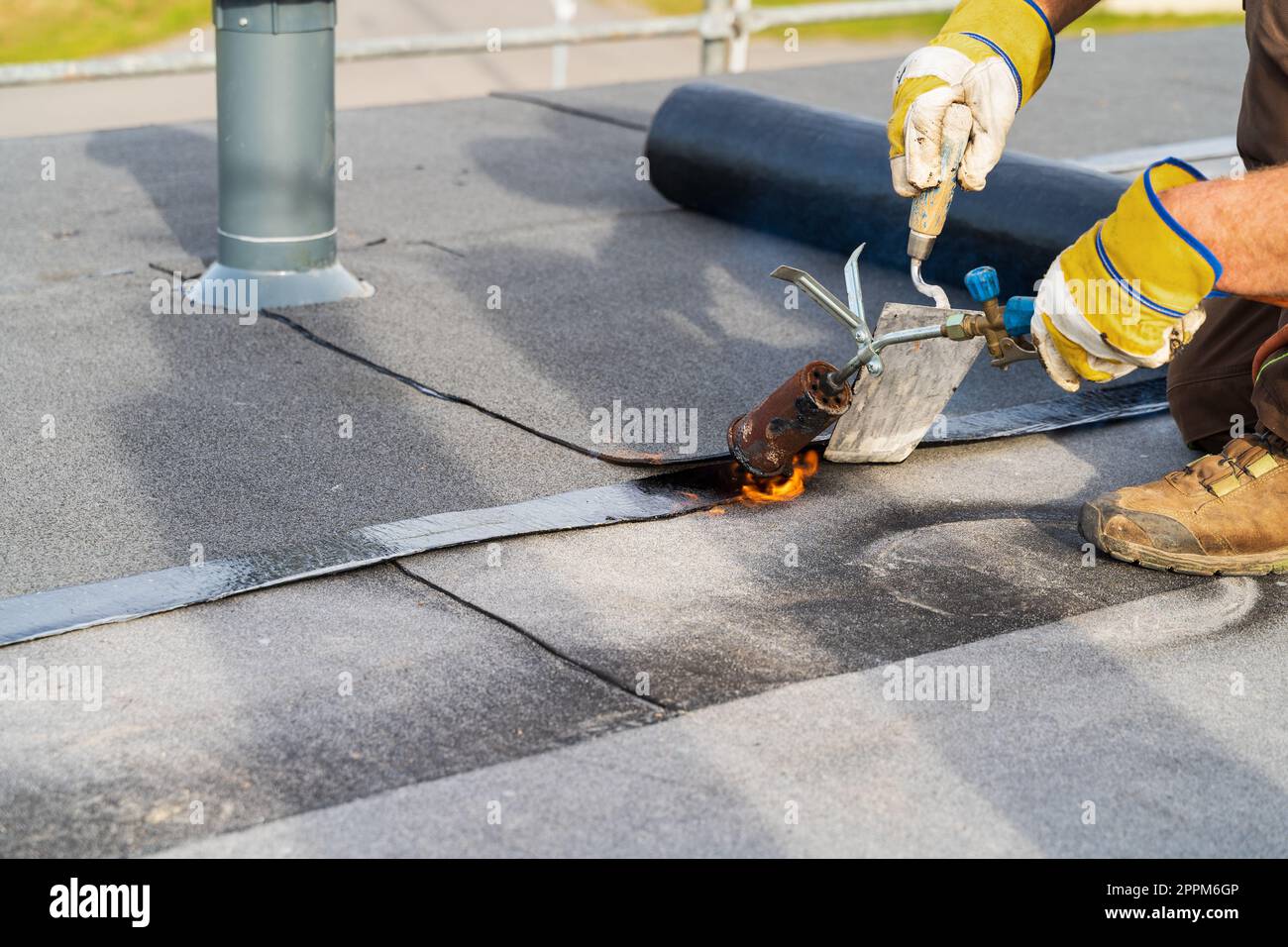 Homme chauffage et fonte de la toiture en bitume installation de la toiture plate. Banque D'Images