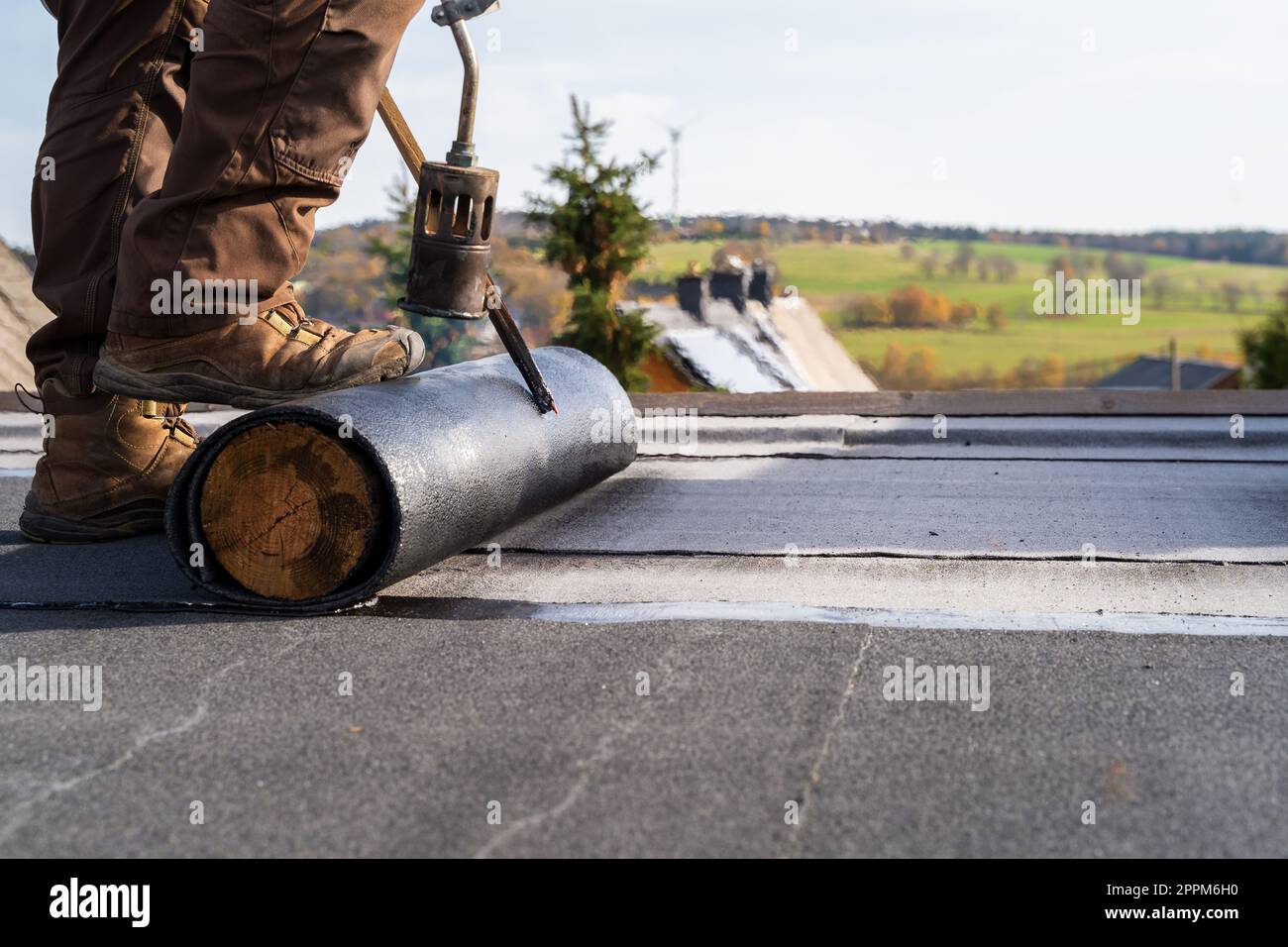 Ouvriers chauffage et fonte de la toiture en bitume installation de la toiture plate. Banque D'Images
