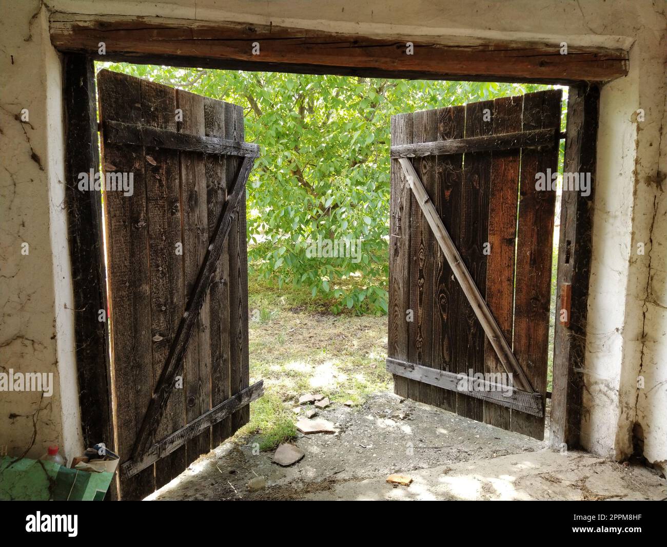 Belle vieille porte ouverte en bois. Vue intérieure de la chambre. Portes de crèche, stalle pour bétail ou garage. Poutres en bois et embrasure de porte. Greens d'été de la porte Banque D'Images