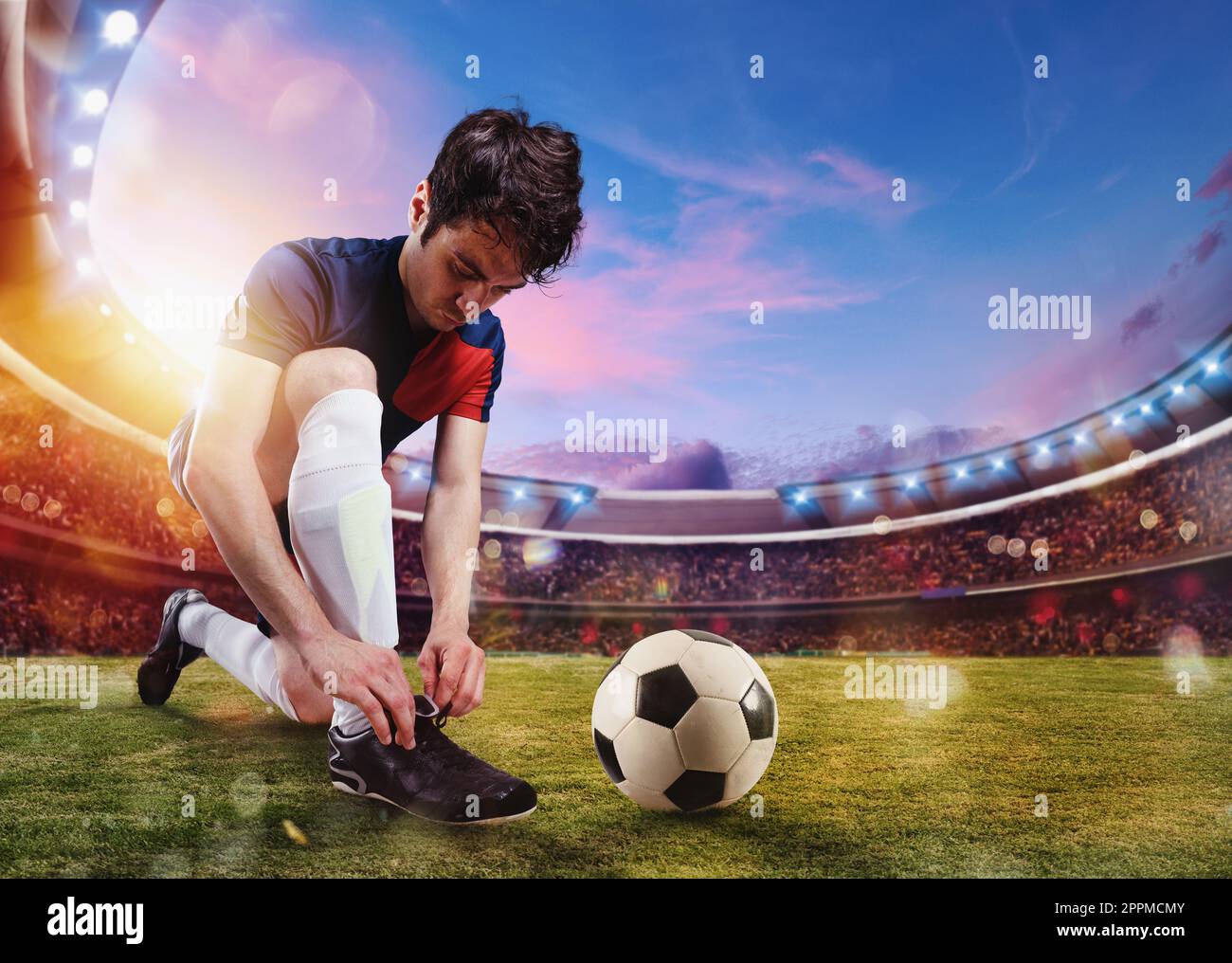 Le joueur de football attache ses chaussures de football prêtes à jouer au stade Banque D'Images