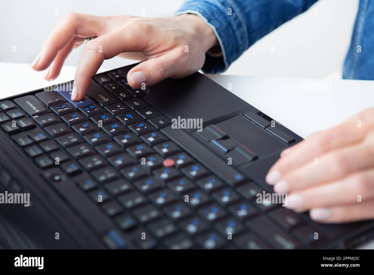 La fille travaille sur un ordinateur portable. Freelance, télétravail, mains sur le clavier. Vue d'en haut. Banque D'Images