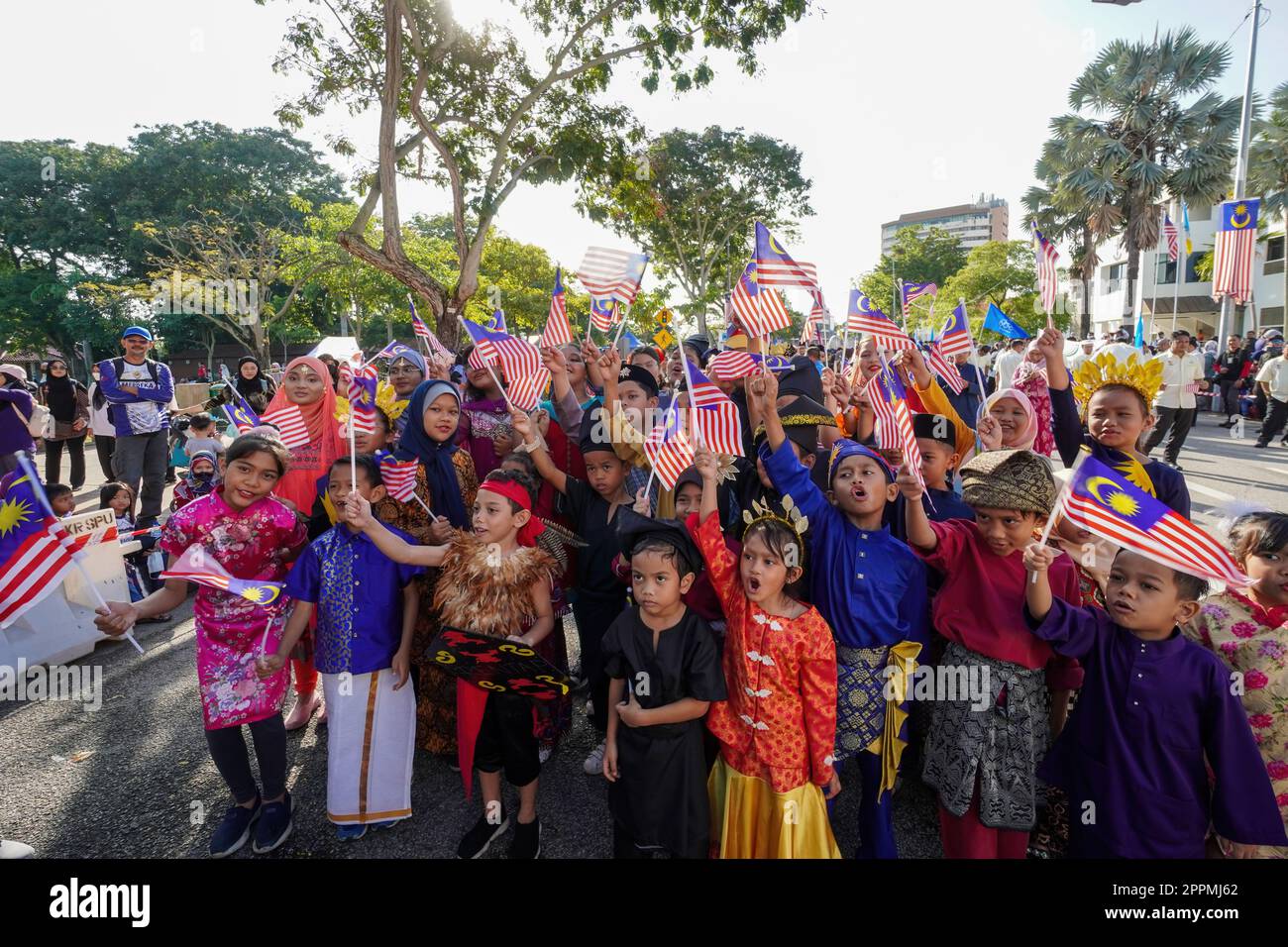 Groupe d'enfants portant le costume traditionnel hisser le drapeau de la Malaisie Banque D'Images