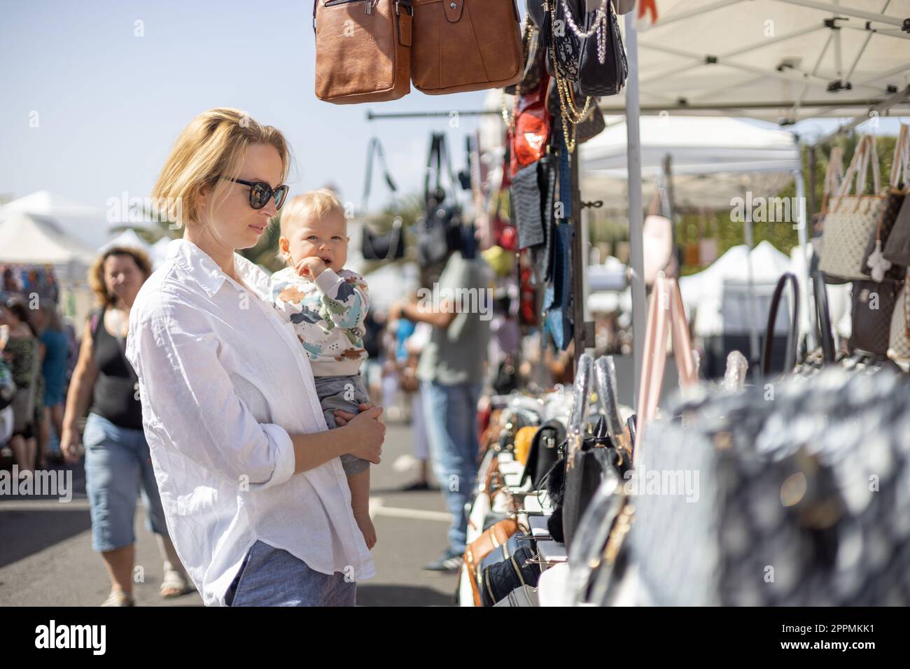 La mère hante son bébé garçon enfant en train d'échecing des articles au marché aux puces du dimanche. Banque D'Images