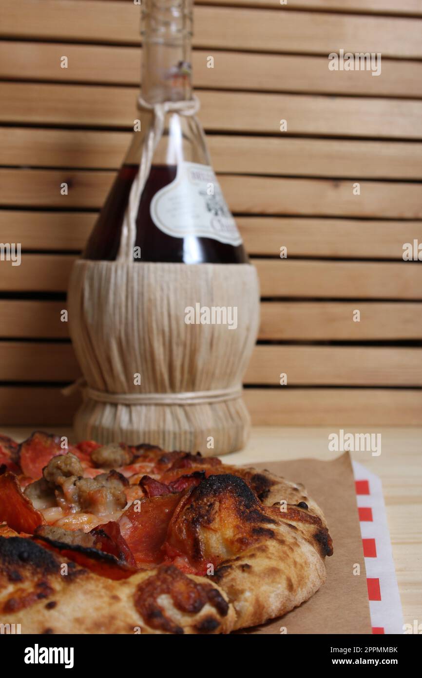 Pizza fraîche sur une table en bois au restaurant avec une bouteille de Chianti en arrière-plan Banque D'Images