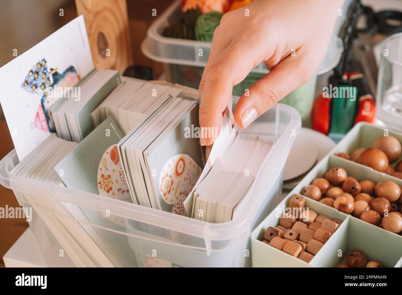 Photo recadrée de mains de femme préparant et choisissant la carte de modèle de boîte transparente pour le paquet de livraison de perles en bois Banque D'Images
