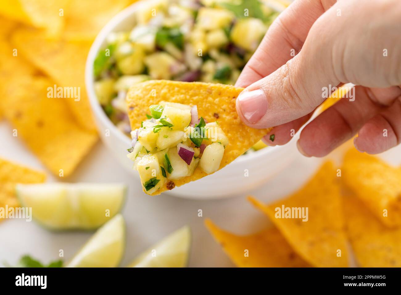 Ananas frais, oignon rouge et salsa de jalapeno dans un bol avec des chips de tortilla en étant scopé avec une puce Banque D'Images