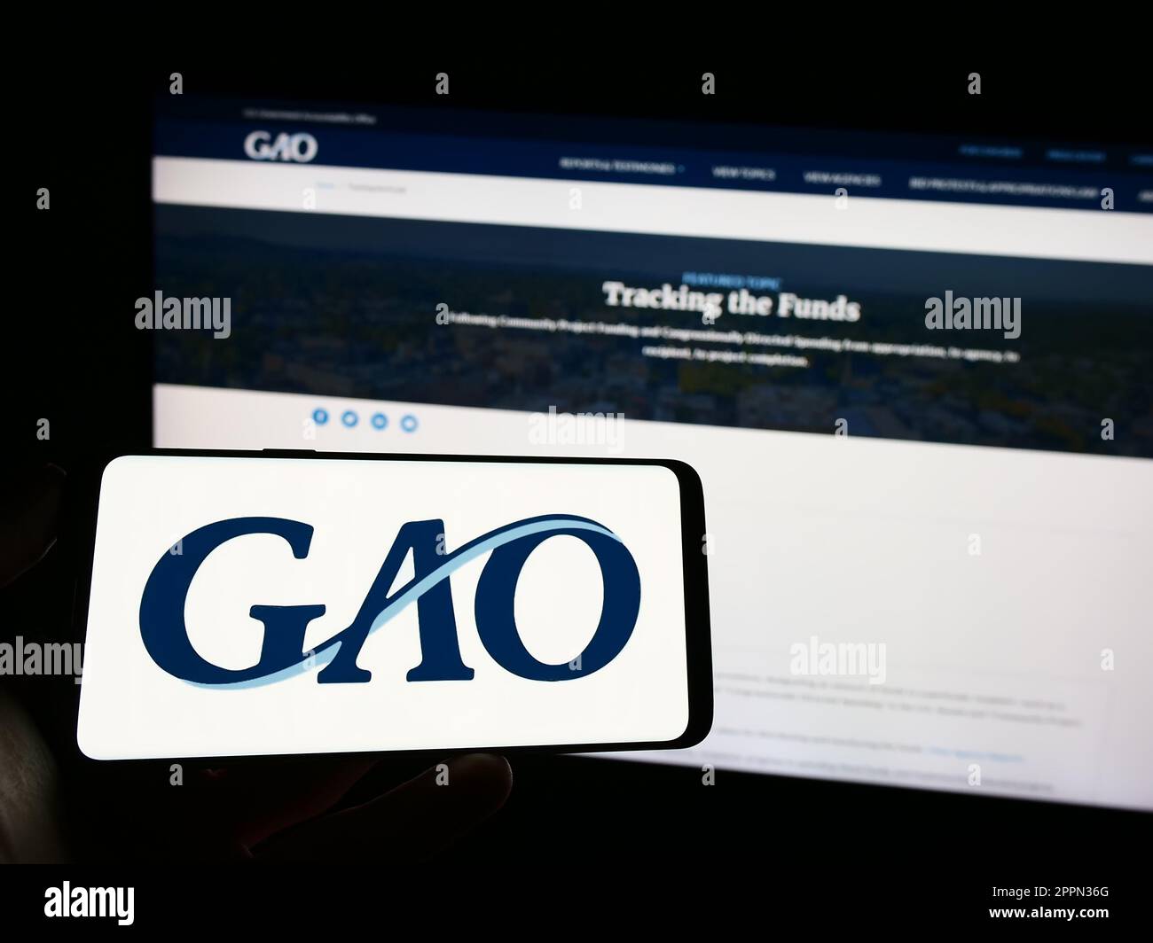 Personne tenant un téléphone portable avec le logo de l'Office de responsabilité du gouvernement des États-Unis (GAO) à l'écran devant la page Web. Mise au point sur l'affichage du téléphone. Banque D'Images
