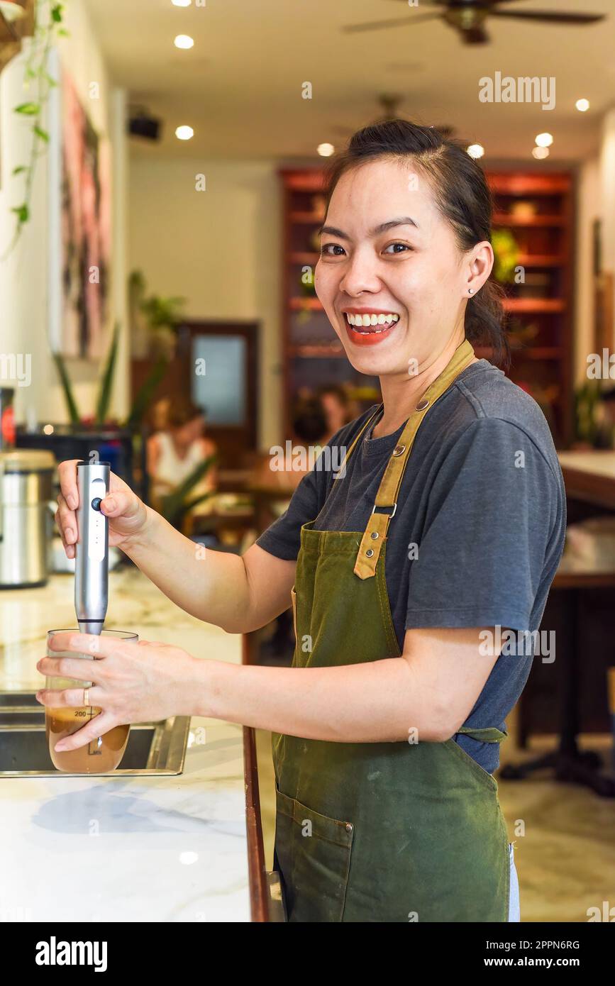 Barista vietnamien utilisant un batteur pour le lait condensé dans une tasse en verre pour préparer le café vietnamien SUA Banque D'Images
